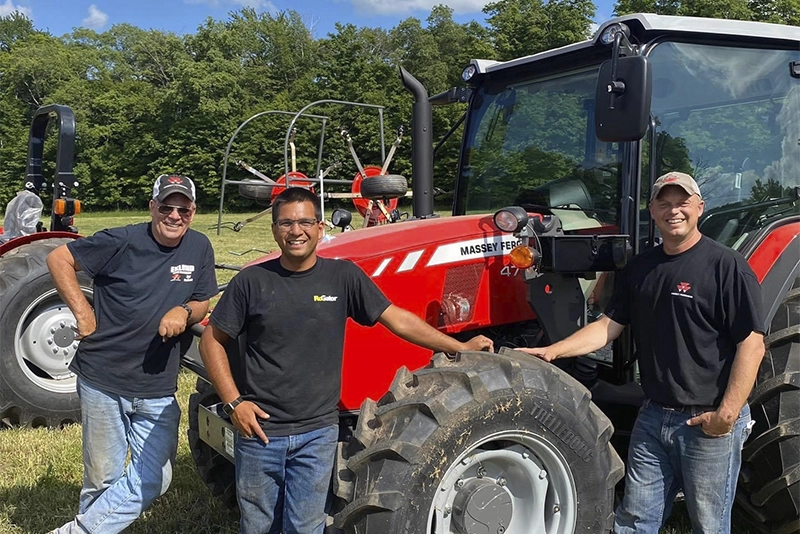 Eklund Farm Machinery team members standing beside a Massey Ferguson tractor in a field in Stamford, NY